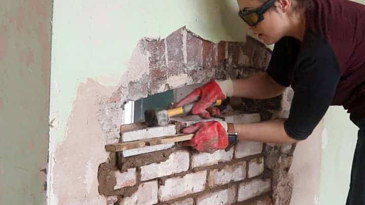 using a club hammer to tap on bricks