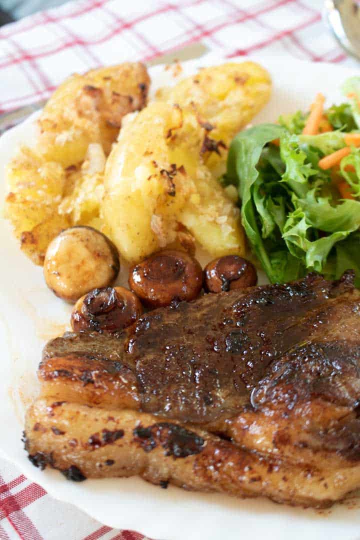 Side shot of crushed potatoes with sirloin steak, salad and mushrooms