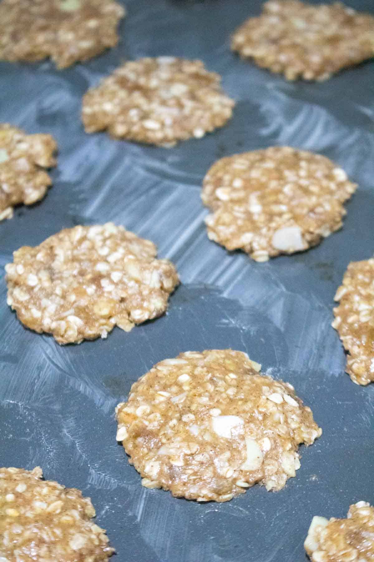 buttered bakig sheet with Anzac biscuits flattened