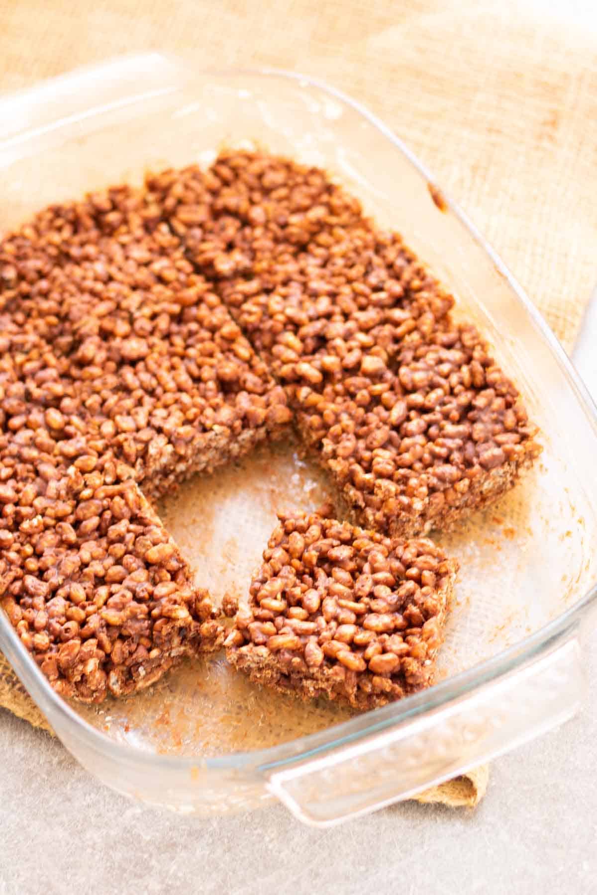 cutting rice krispie squares in a baking dish