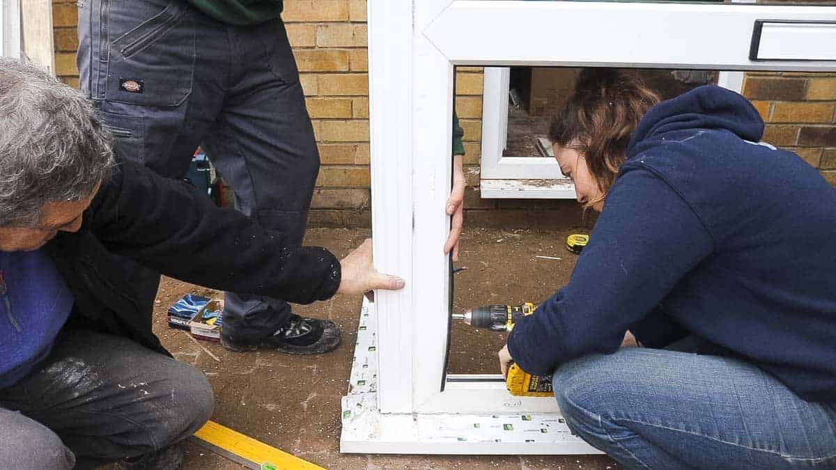 Drilling and screwing window frame to bay pole.