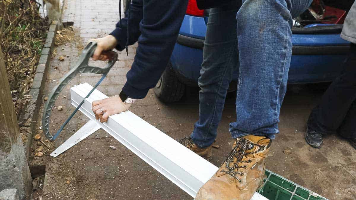 Hack sawing a bay pole down to the same height as a UPVC door.
