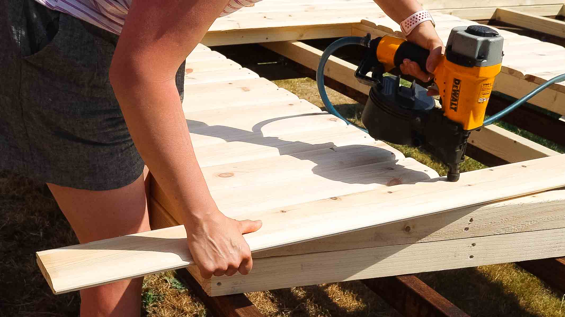 nailing a long strip of shed cladding with a nail gun