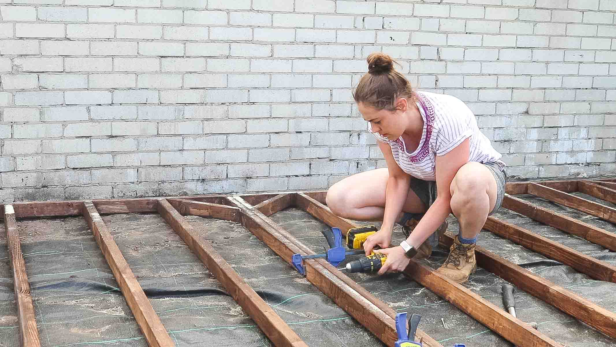 Woman clamping and screwing shed base sections together