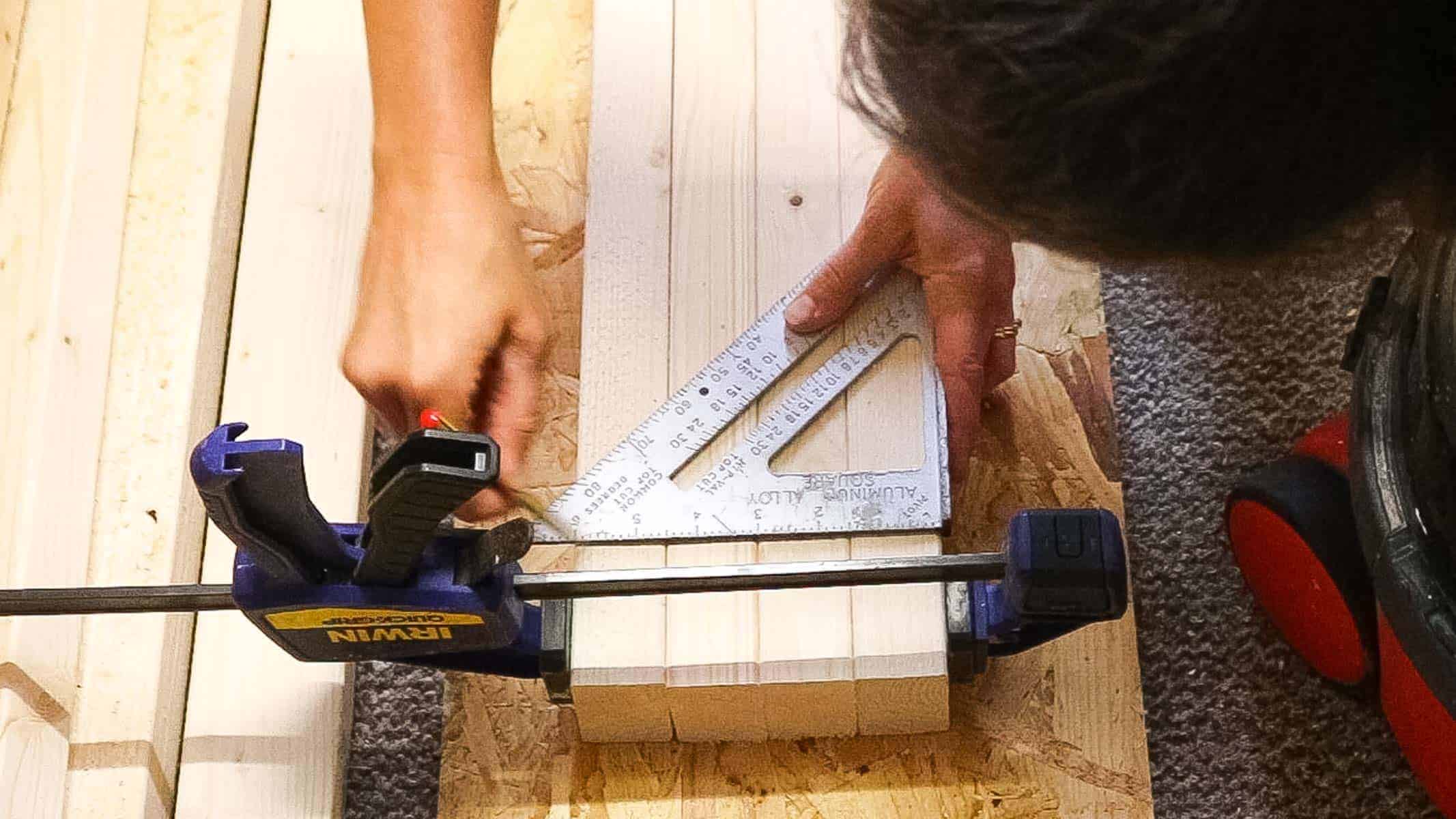 Vikkie Lee drawing along a speed square to mark shelving