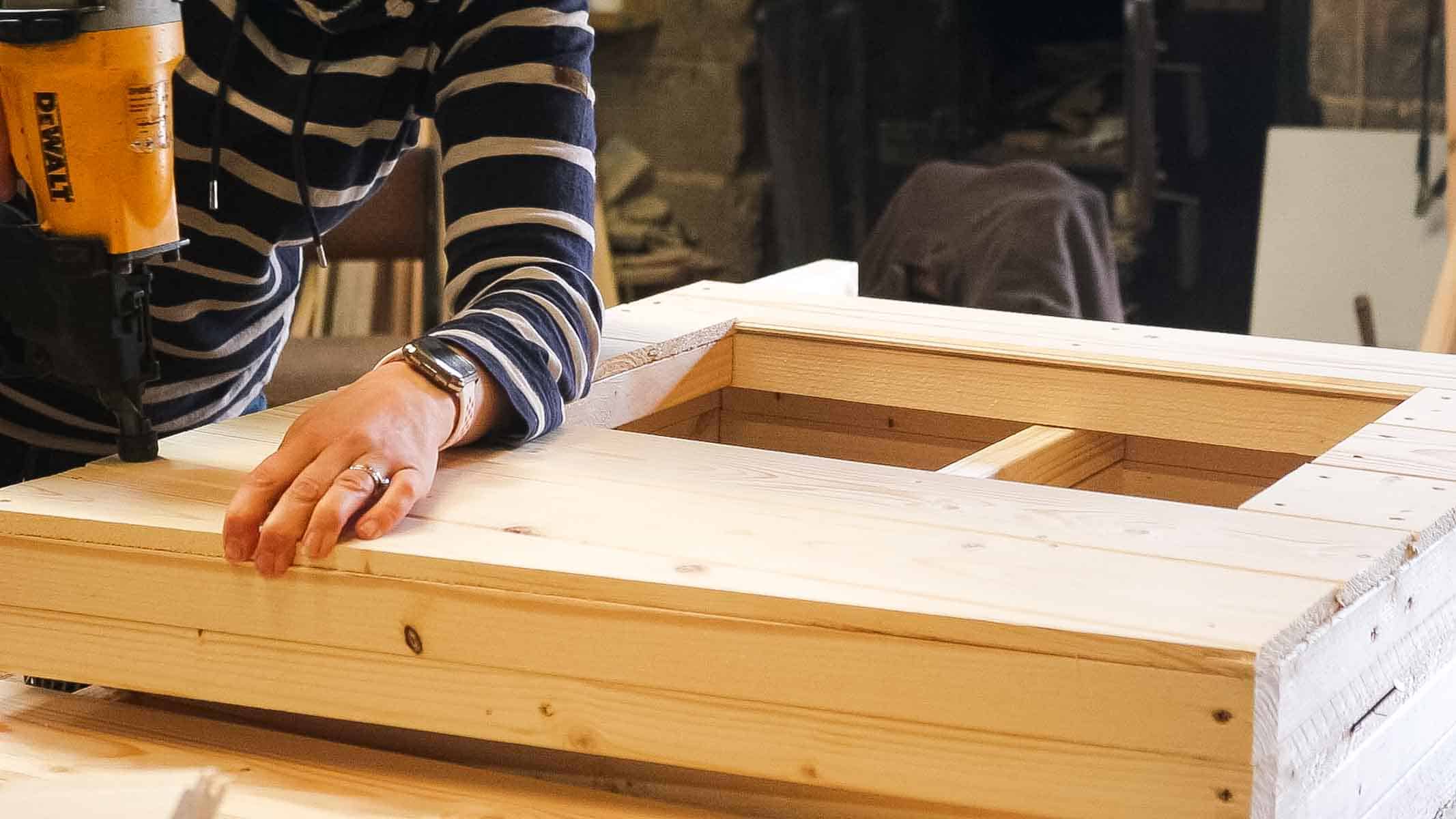 attaching top bit of cladding with a nail gun to chicken coop for ITV's Love Your Weekend