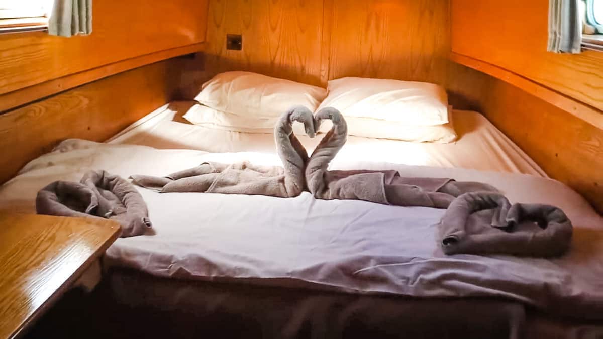 Bed with towel swan at the front of a hire boat