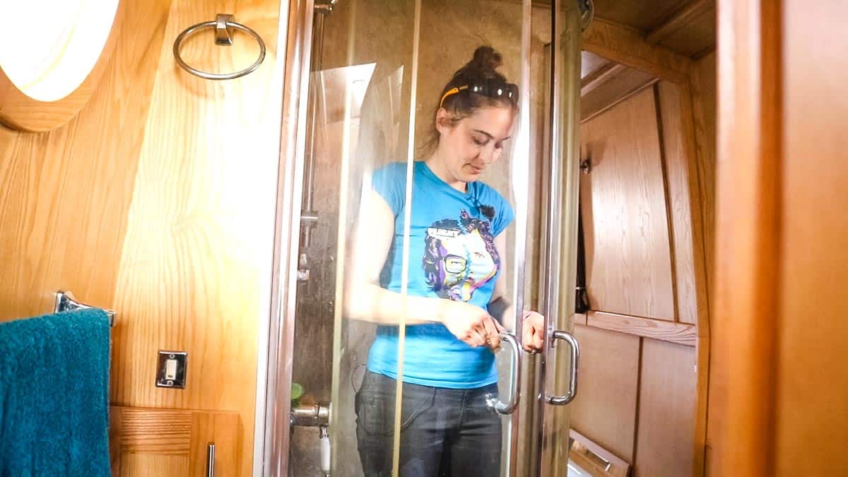 Woman stood fully clothed in narrowboat shower for size demonstration