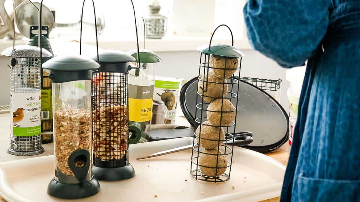Filling Do It Yourself Bird Feeders with peanuts, seeds, fat balls in mesh cages and hanging tubes