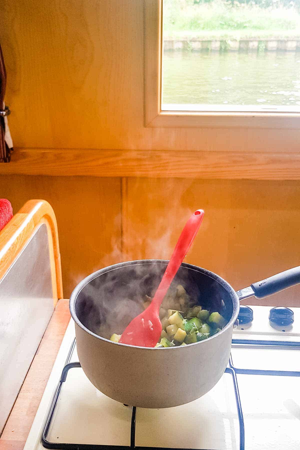 Frying zucchini in an English narrowboat kitchen on the hob