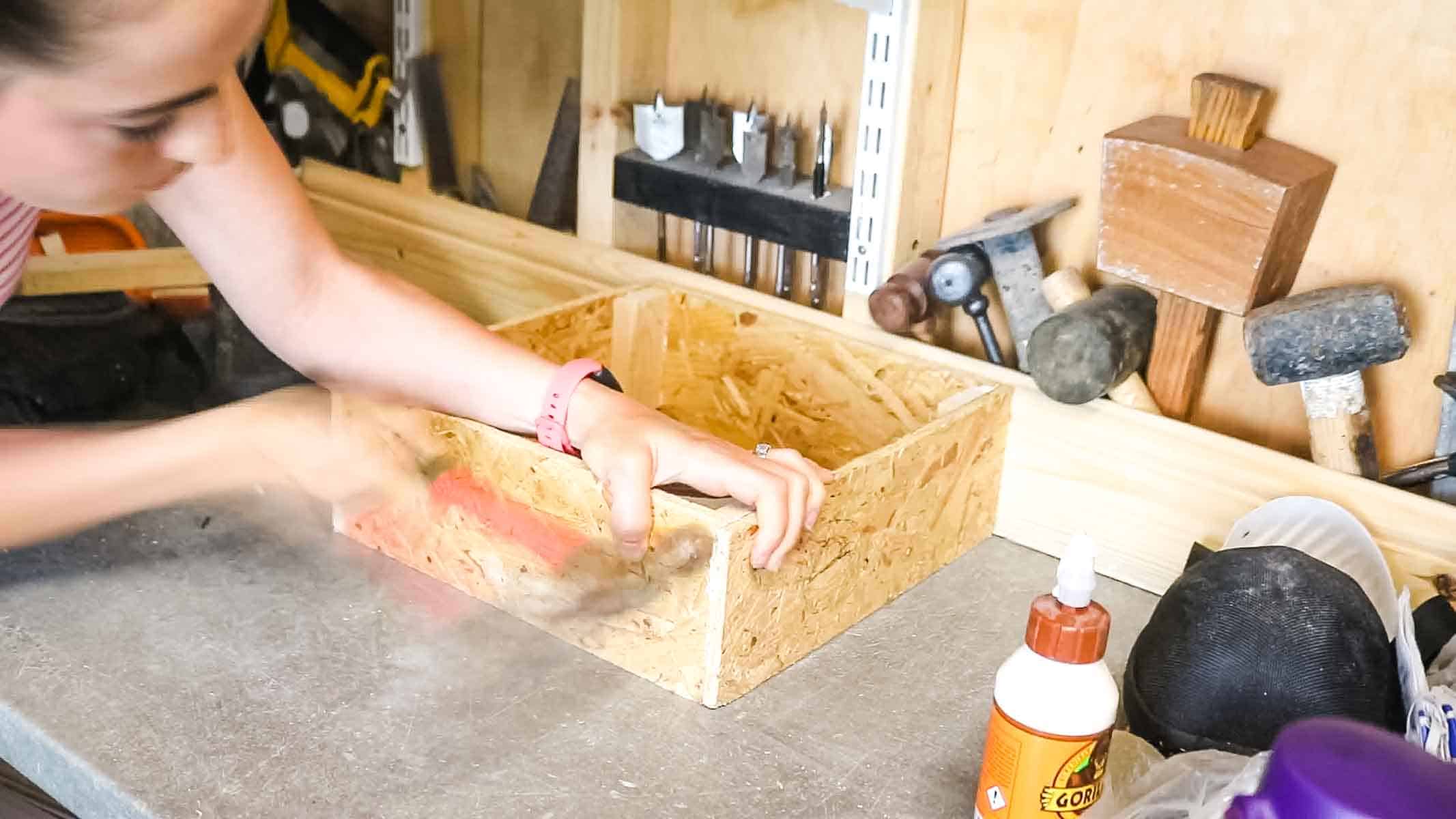 Woman making box using OSB offcuts and studding