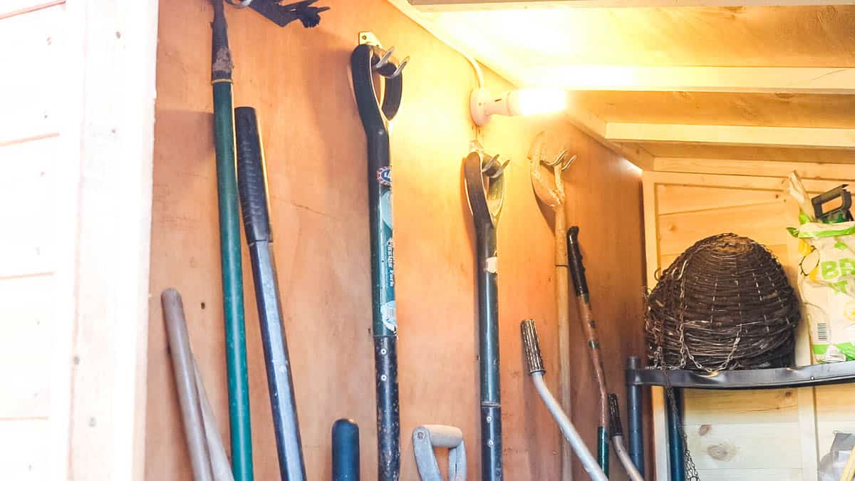 garden tools hanging on hooks in a lean to shed