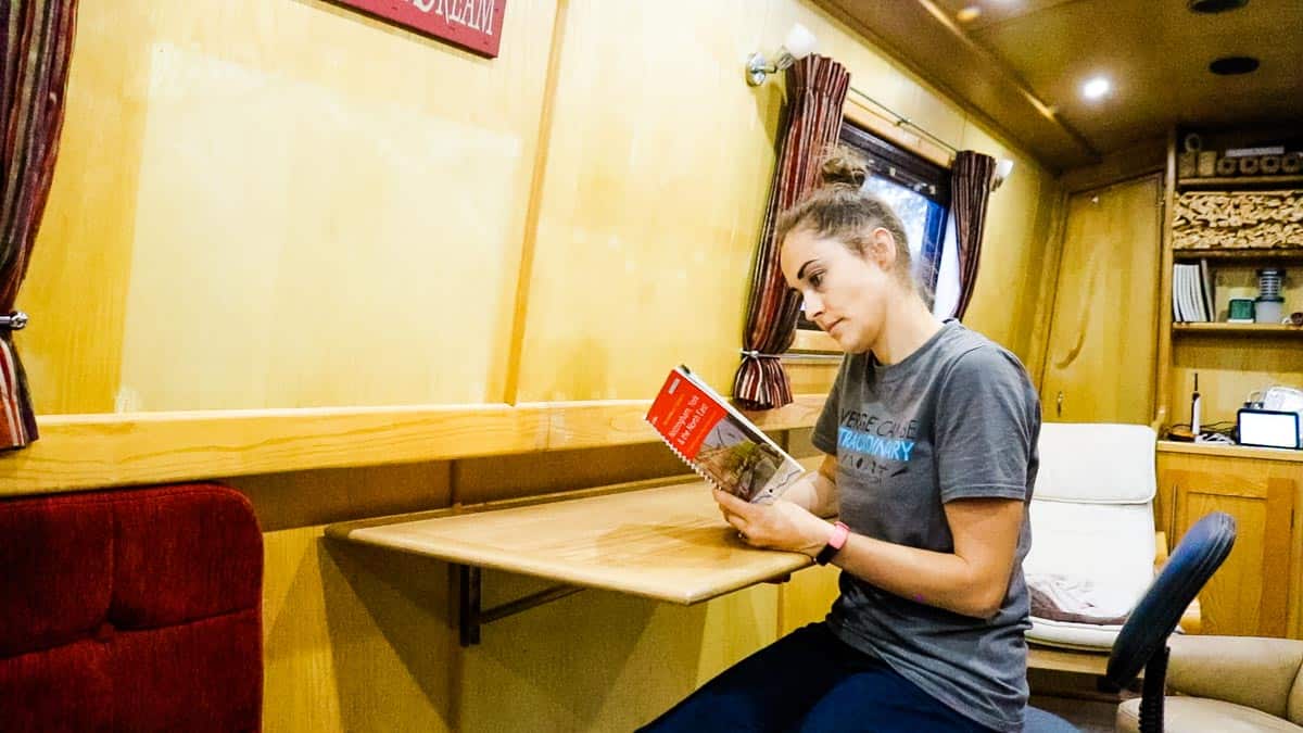 Woman sat reading at an oak DIY Murphy desk table in a narrowboat.