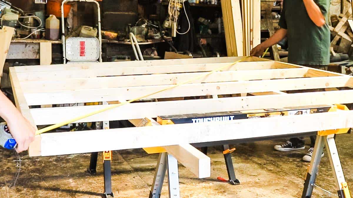 Two people checked a shed base for square on Toughbuilt sawhorses