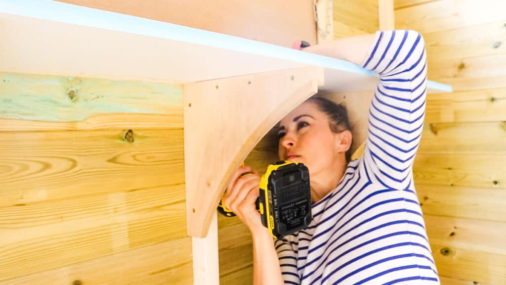 Woman making easy plywood shelves screwed to shed spars