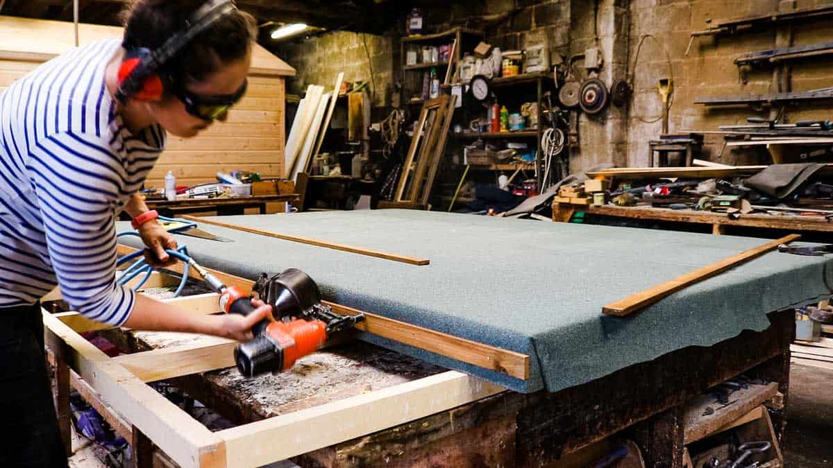 Woman felting a shed roof in a woodyard
