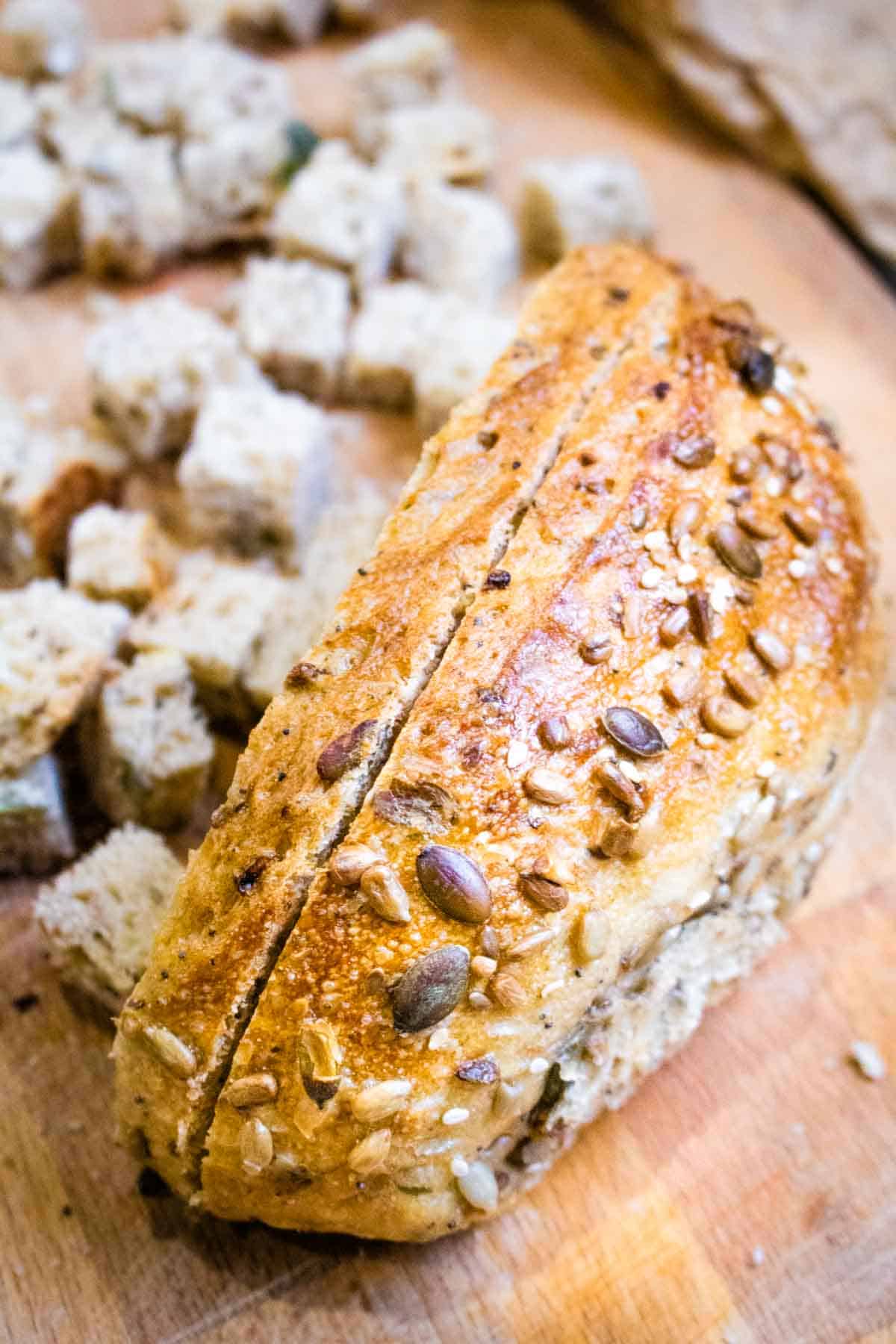 Sliced 7 seeded sourdough, partially diced into cubes on a wooden chopping board