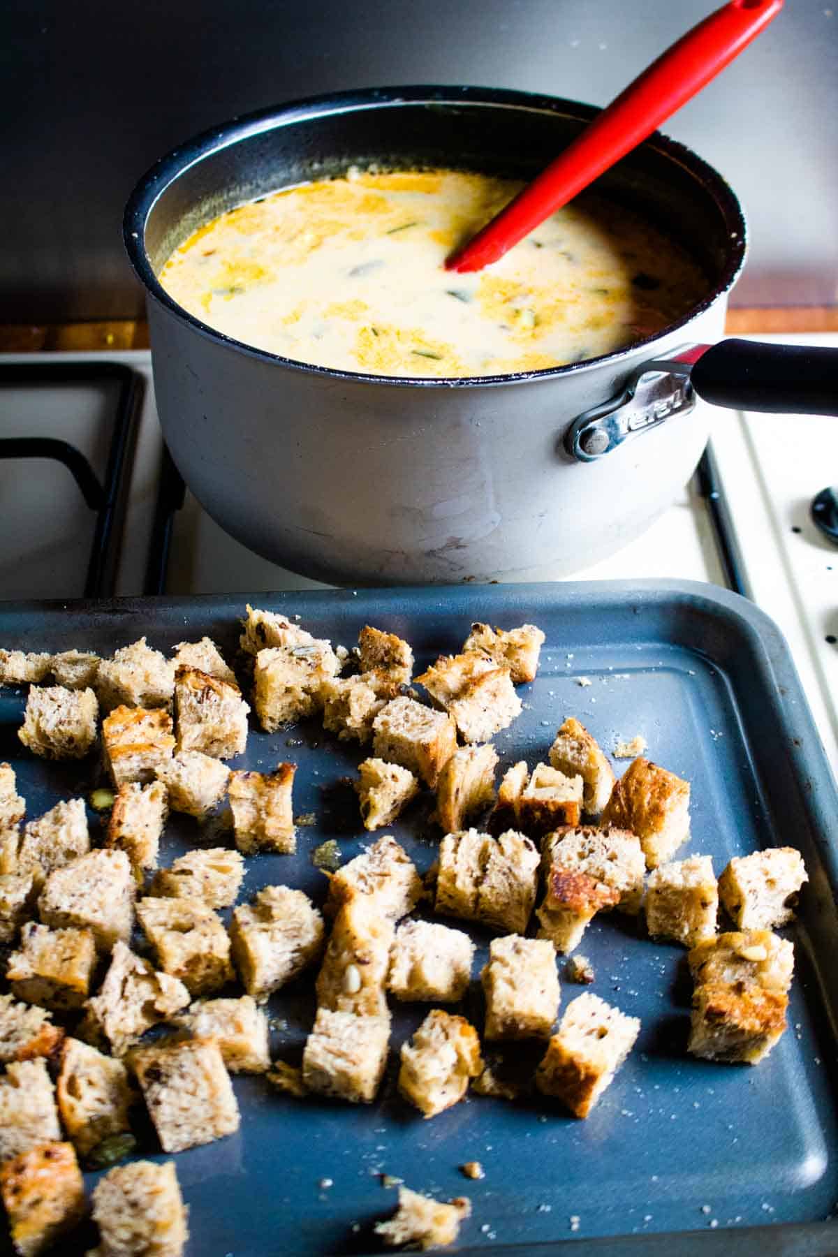 Soup cooking in a saucepan before toasted sourdough is stirred in