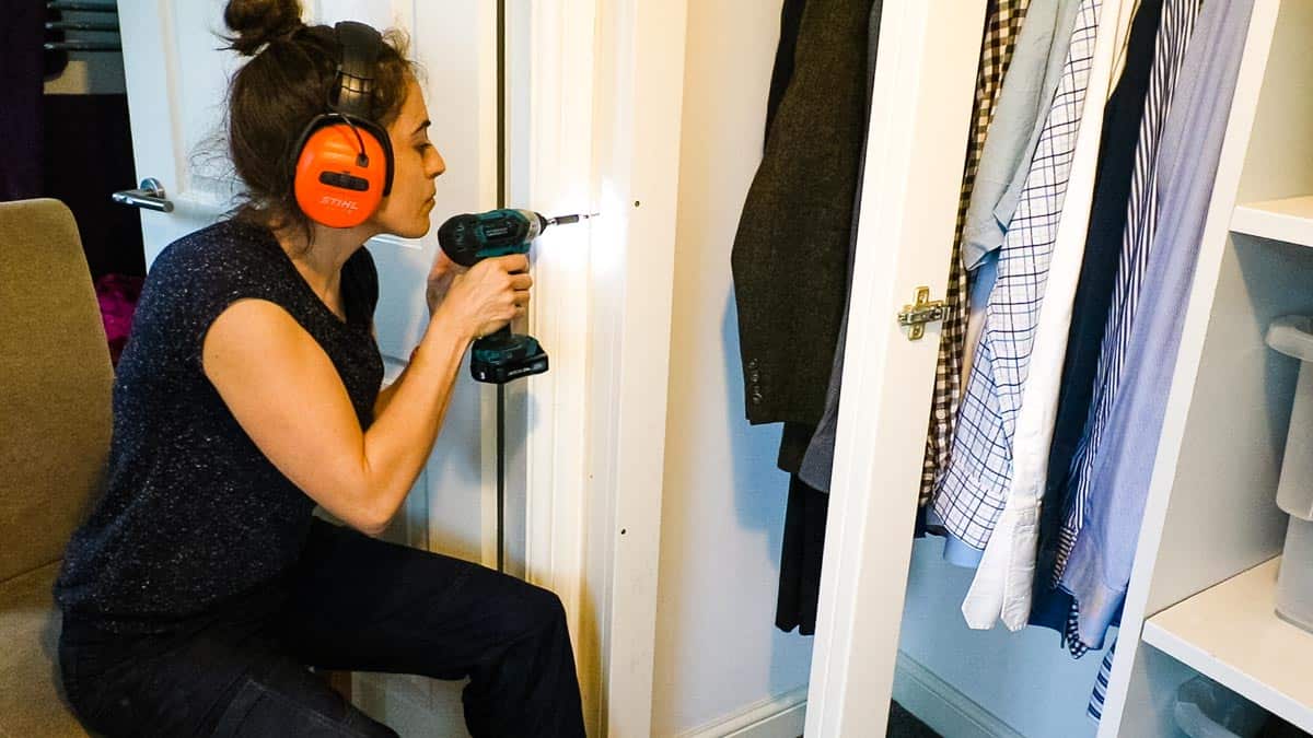 Woman screwing wardrobe framework to batten