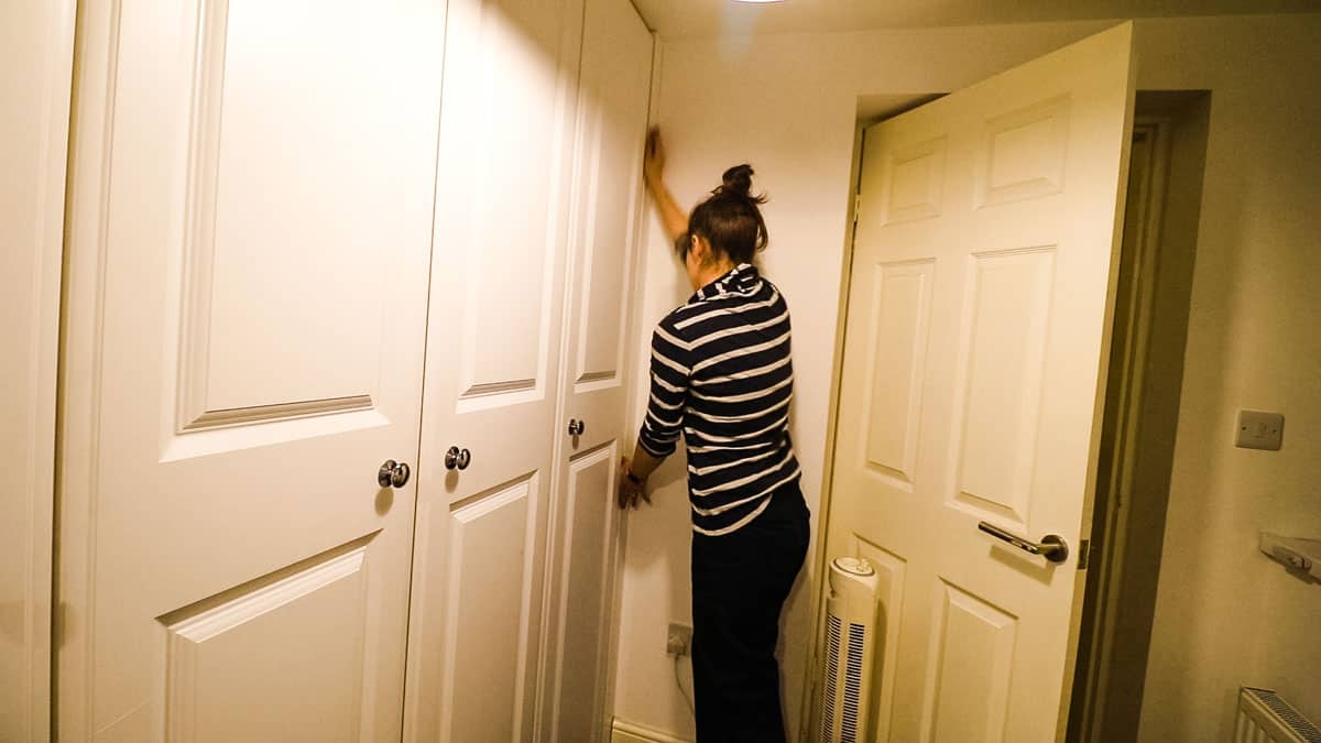 Woman sticking wardrobe trim piece over filler piece to hide screws