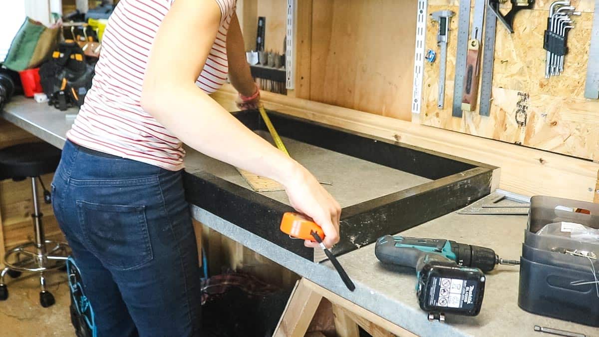Woman making a homemade DIY dog bed frame square using a tape measure