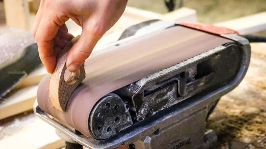 Sanding a homemade page book holder on an upside down belt sander