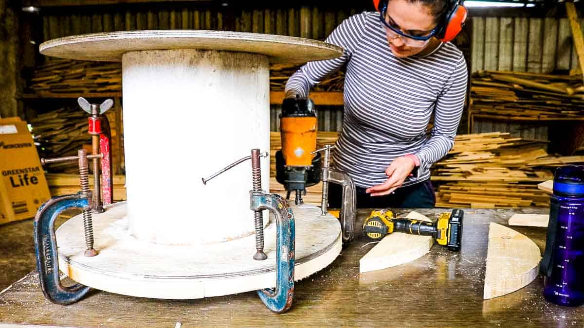 Woman nailing clamped pieces of pallet wood to a wire spool