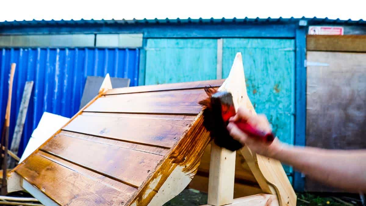 Staining the roof of a homemade wishing well with coloured wood preserve