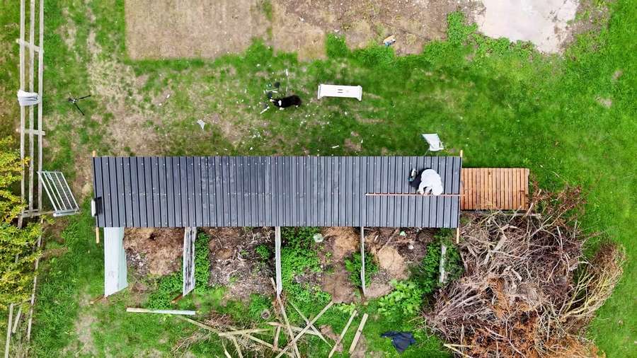 Overhead view showing the length of the completed metal roof along the existing fence.